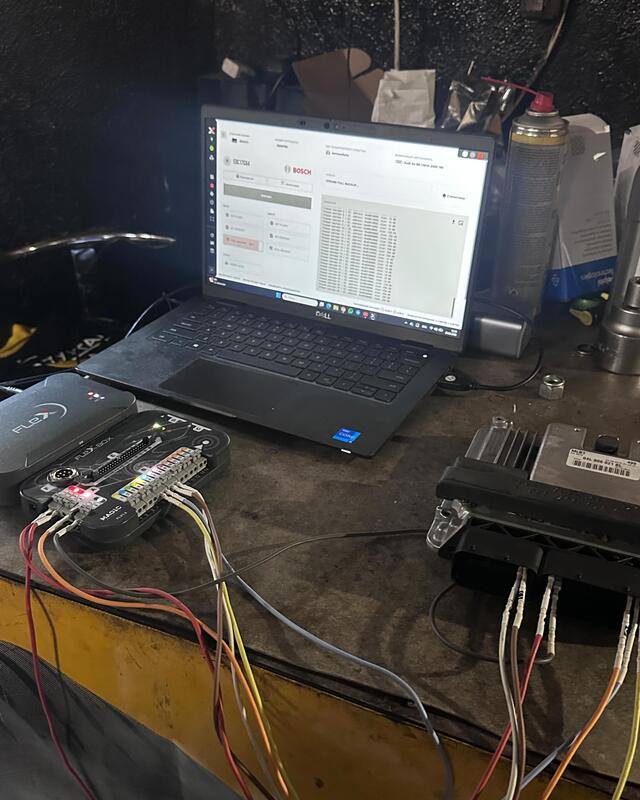 Sterownik silnika na stole warsztatowym, obok laptop z programem Bosch i adapter