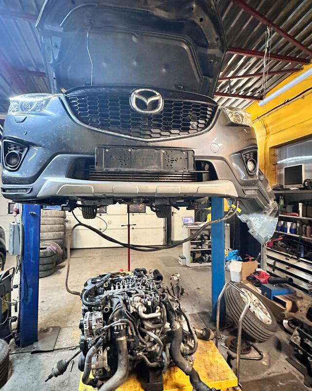 Mazda CX-5 na podnośniku, obok wyjęty silnik na żółtym stojaku